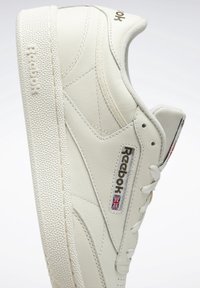Vit Reebok lädersneaker som visar sidoprofil med pr präglad logotyp, Union Jack-flagga och texturerad gummisula.