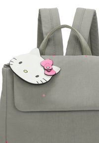 Mochila gris con cierre de solapa, que presenta un acento en forma de gato blanco con un lazo rosa. Estrellas luminosas decoran la superficie. Tejido texturizado.