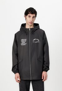 Black hooded jacket with a zipper, featuring two front pockets and printed logos in white. Smooth fabric, elastic cuffs, and relaxed fit.
