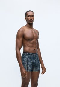 Boxers med sort midjebånd som har "BJÖRN BORG" logo, mønstrete i blå og grå diamanter, med fitted design og mykt materiale.