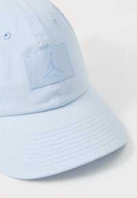 Lyseblå baseballcaps laget av stoff, med en sydd logopatches, buet skjerm og teksturert overflate med synlig søm.