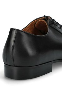 Czarne skórzane buty dostosowane do eleganckich stylizacji, charakteryzujące się gładką teksturą, zaokrąglonym obcasem oraz sznurowanym zapięciem. Wnętrze wykończone jest jasnobrązową podszewką.