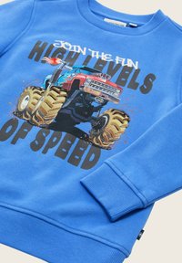 Felpa blu con una grafica di un monster truck che salta, accompagnata dal testo "Unisciti al divertimento ad alta velocità."