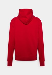 Sudadera con capucha roja mostrada desde la parte trasera con mangas largas y un diseño sencillo sobre un fondo blanco.