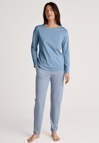 Lichtblauw langslijf topje gekoppeld aan gemusterde blauw-witte pyjamabroek met een geometrisch ontwerp. Zachte, casual stof.