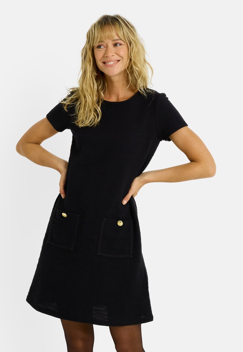 Robe noire en tissu texturé, dotée de manches courtes, d'un col rond et de deux poches avant avec des boutons dorés.