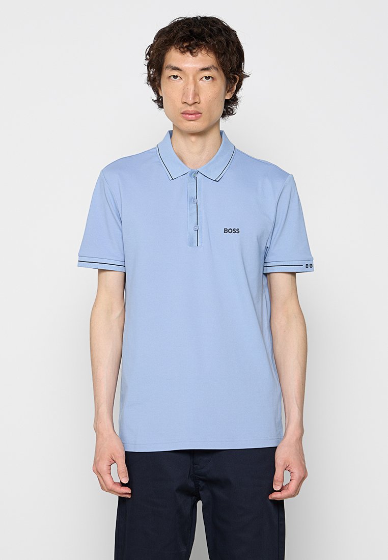 Hellblaues Poloshirt mit Kragen, zwei Knöpfen und kontrastierenden dunkelblauen Streifenakzenten an den Ärmeln. Verfügt über ein kleines schwarzes Logo auf der Brust.