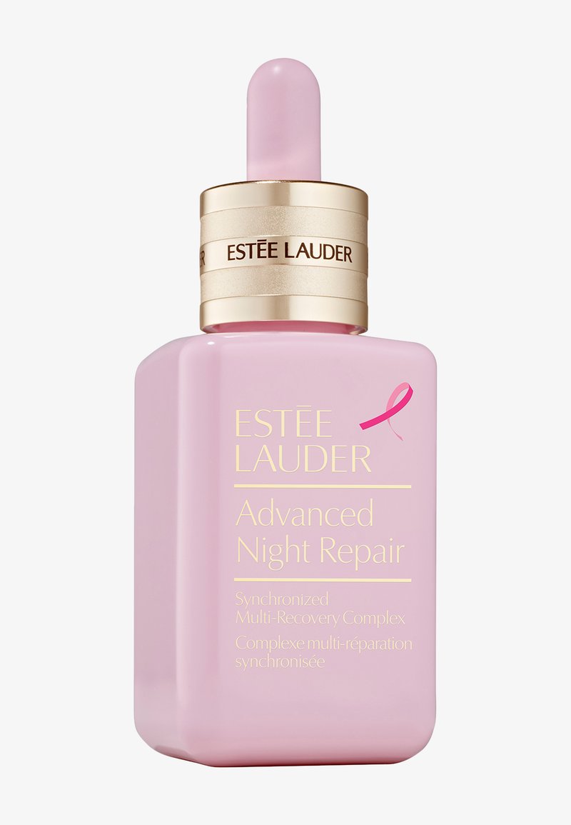 Lyserød glasflaske med et guld bånd og pipette-top. Etiketten har hvid og guld tekst, der detaljerer produktnavnet og fordelene.