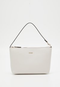 Petit sac à main blanc avec fermeture éclair dorée, logo "GUESS" et sangle noire amovible sur fond blanc.