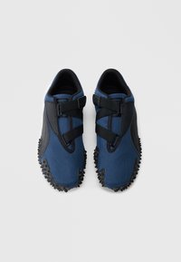 Μπλε υφασμάτινα παπούτσια με μαύρες λεπτομέρειες, με κομψό σχεδιασμό, δύο μαύρες λουράκια στο πάνω μέρος και υφή σόλας από καουτσούκ.