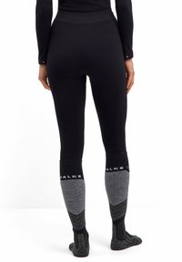 Czarne legginsy z wysokim stanem. Szare, grube skarpetki z wzmocnionym palcem i piętą, z logo marki oraz akcentami w geometrycznym wzorze.
