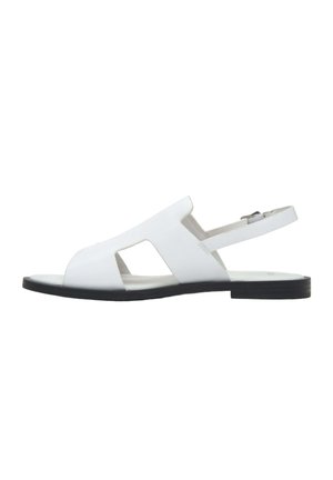 Witte leren platte sandalen met open teen, uitgesneden zijkanten en verstelbare enkelriem op een zwarte zool.