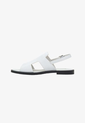 Fehér bőr nyitott orrú lapos szandál kivágott oldalakkal és állítható bokapánttal fekete talpon.
