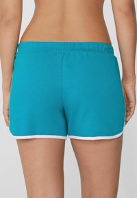 Pantaloni sportivi turchesi con una texture morbida, dotati di un bordo bianco lungo l'orlo e una vita elastica per il massimo comfort.