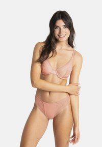 Ensemble soutien-gorge en dentelle et slip assorti en rose doux. Le soutien-gorge présente une forme triangulaire, des détails en dentelle transparente et des bretelles réglables.