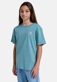 Camiseta de algodón color azul verdoso con mangas cortas y cuello redondo. Presenta un pequeño logo naranja de "Element" y un gráfico de un árbol en el lado izquierdo del pecho.