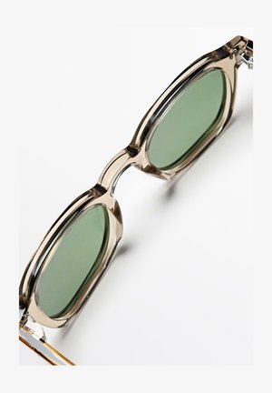 Gennemsigtige beige rektangulære solbriller med grønne tonede linser mod en hvid baggrund.