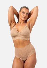 Kukatut bralette ja korkeavyötäröiset alushousut vaaleassa beessä. Ominaisuuksia ovat reunat, joissa on aaltoilua ja kukkakuviot. Pehmeä rakenne ja säädettävät hihnat.