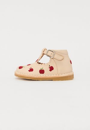 Tan leather shoe with a T-strap, adjustable buckle, and small cut-outs. Decorated with red embroidered apple patterns on the upper.