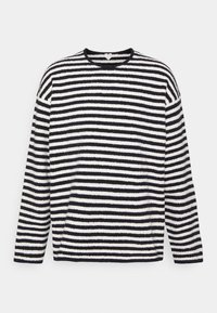 Musta-valkoisessa raidallisessa pitkähihnaisessa poolo-paidassa on pehmeä, teksturoitu kangas. Pyöreä kaula-aukko ja väljä istuvuus. Vaakasuorat raidat vaihtelevat leveydeltään.