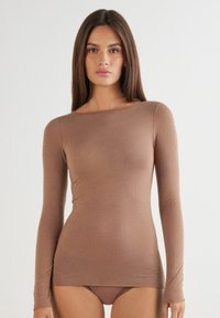 Haut à manches longues en tissu marron doux, avec un décolleté bateau et une silhouette ajustée. Texture lisse et détails minimalistes.