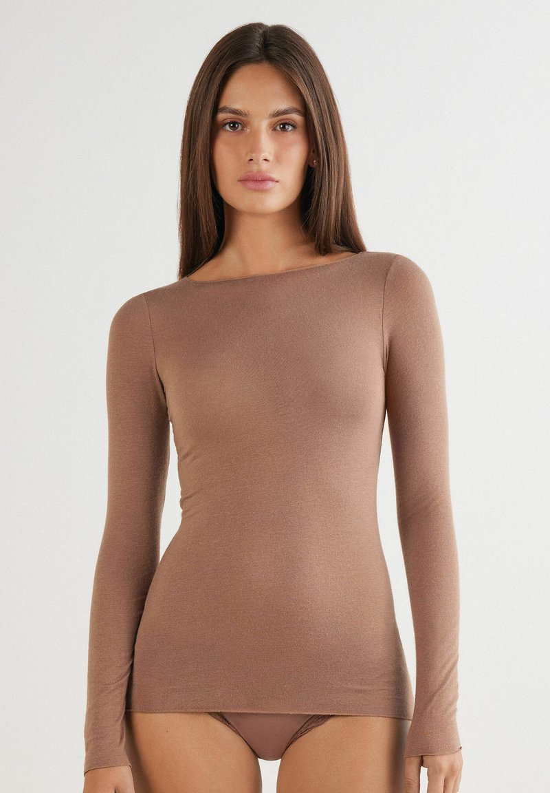 Haut à manches longues en tissu marron doux, avec un décolleté bateau et une silhouette ajustée. Texture lisse et détails minimalistes.