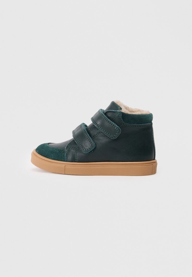 Grüner Leder-Hochschuh mit beigen Klettverschlüssen, weicher Innenausstattung und Sohle aus Gummi. Mit Wildlederakzenten an Zehen und Knöchel.