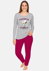Maglietta grigia a maniche lunghe con grafica "PEANUTS CUDDLE SOCIETY", abbinata a pantaloni aderenti rosa. Tessuto morbido, design casual e vestibilità rilassata.