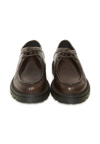 Paire de chaussures à lacets en cuir marron foncé avec semelles épaisses en caoutchouc noir, vues de face sur un fond blanc.