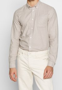 Lange mouwen, lichtbeige overhemd met knopen en een borstzak, gemaakt van een gestructureerde stof, gecombineerd met off-white broek.