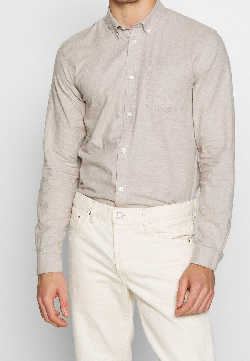 Lange mouwen, lichtbeige overhemd met knopen en een borstzak, gemaakt van een gestructureerde stof, gecombineerd met off-white broek.