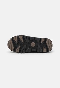 Black and brown rubber sole with a textured pattern. Features deep treads and a central circular design for traction.