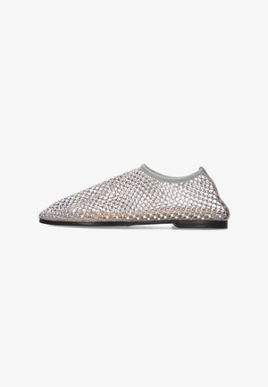 Chaussure slip-on en maille avec un dessus gris courbé, un corps transparent texturé et une semelle noire plate. Présente un motif de tissage ouvert unique.