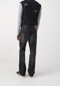 Lösa svarta jeans med en blekt textur, fyra fickor och rak benform. Matchas med en ribbad ljusgrå långärmad topp.