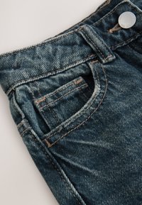 Džínové šortky s tmavomodrým efektom, vybavené predným vreckom, medeným prešitím, kovovým gombíkom a ošúchanými detailmi na okrajoch.