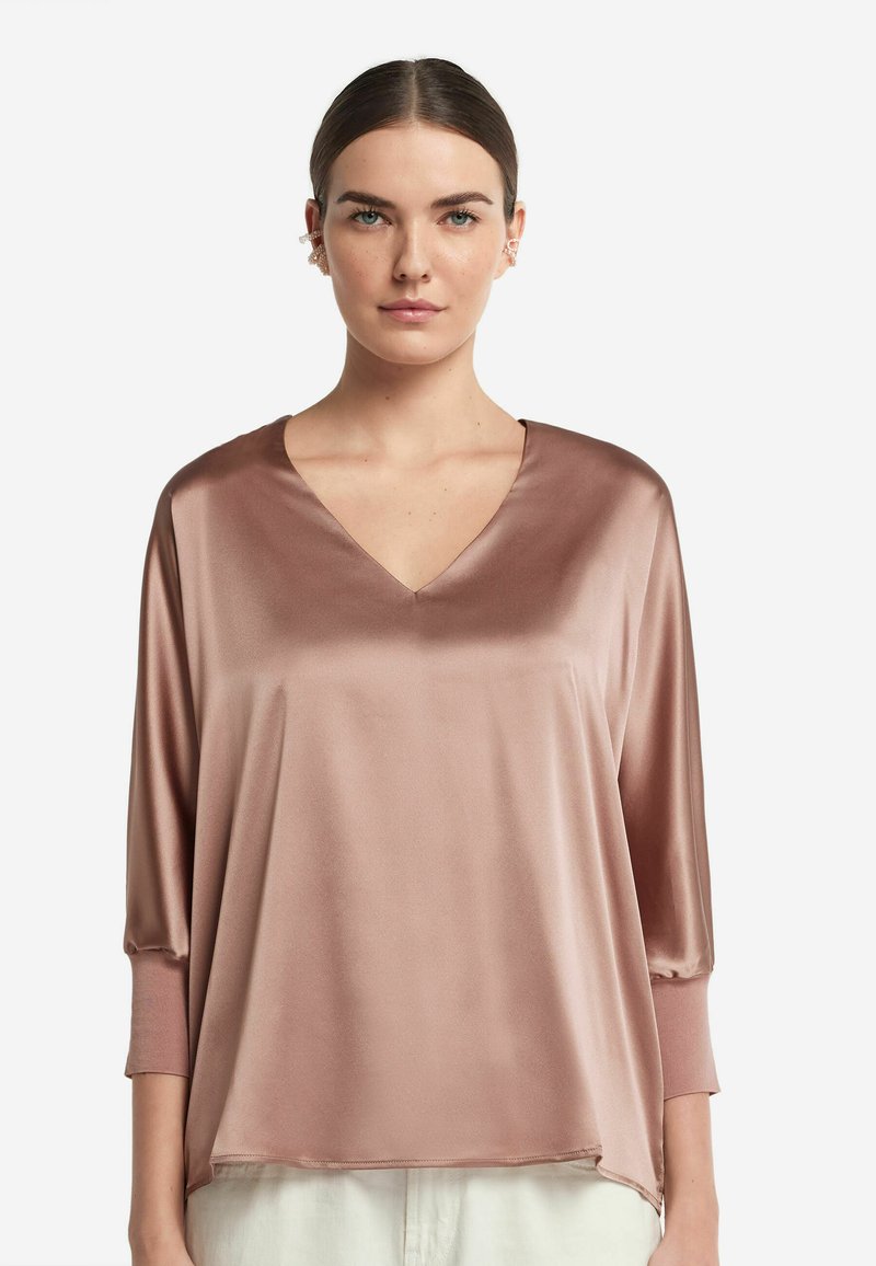 Satin V-Ausschnitt-Oberteil in staubigem Rosenfarben mit 3/4-Ärmeln. Weicher Stoff und lockere Passform, der Saum reicht unter die Hüften.