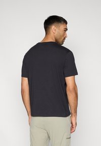 Μαύρο κοντομάνικο μπλουζάκι από μαλακό, ελαφρύ ύφασμα, με στρογγυλή λαιμόκοψη και άνετη γραμμή, φαίνεται από πίσω.