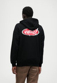 Black hoodie with a drawstring, featuring a large white and red logo on the back. Soft texture, standard fit, ribbed cuffs and hem.