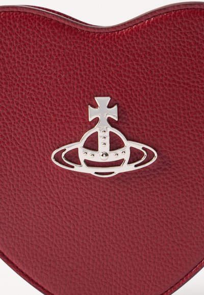 Borsa a tracolla in pelle rossa con texture, a forma di cuore, caratterizzata da un logo di corona argento con design a croce e anello come dettaglio distintivo.