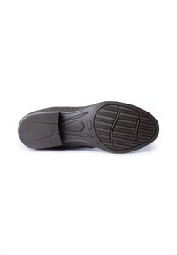 Suela de zapato de goma negra con patrones de agarre texturizados, con forma redondeada y marcas de indentación. Logo grabado cerca del talón.