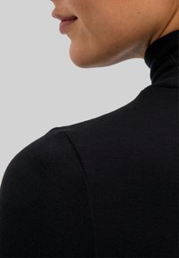 Zwarte high-neck top in geribbelde textuur, met een slim fit ontwerp en een gladde afwerking. Zichtbare naaddetails en een strakke silhouet.