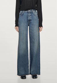 Jeans o szerokich nogawkach w średnim niebieskim odcieniu, z wysokim stanem, kieszeniami z przodu i postrzępionymi brzegami dla dodatkowej tekstury.