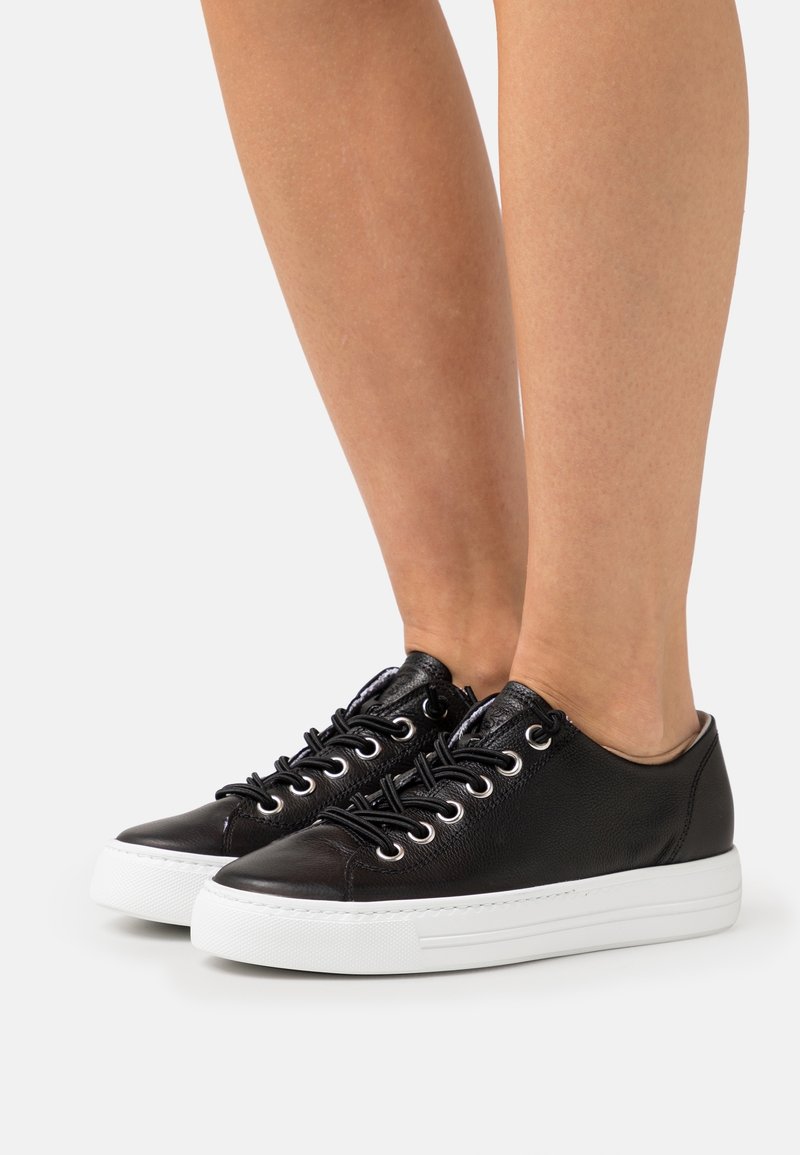 Black leather sneakers with white rubber soles, featuring round laces and metallic eyelets, smooth texture, and a low-top design.
