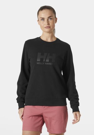Czarny sweter z okrągłym dekoltem i ściągaczami na rękawach, z matowym czarnym logo "HELLY HANSEN" z przodu, w zestawie z różowymi szortami.