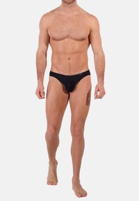 Schwarze Herrenunterhosen mit vertikalem Rippmuster, elastischem Bund und minimaler Bedeckung. Material aus Baumwollmischung mit glatter Textur.