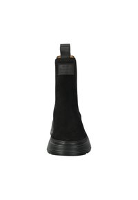 Botines tobilleros de ante negro con una lengüeta y suela de goma texturizada. Cuenta con una etiqueta de marca texturizada en la parte trasera. Diseño suave.