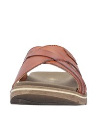 Sandale à glissière en cuir marron avec des sangles croisées, une semelle intérieure rembourrée et une semelle extérieure en caoutchouc texturé avec un design subtil.