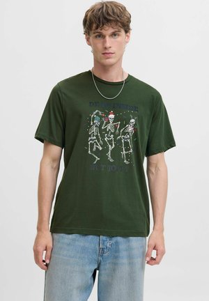 Donkergroene katoenen t-shirt met skeletillustraties en feestelijke accenten, tekst "DODEN IN DE BUITEN, MAAR VREUGDIG," en een ronde hals.