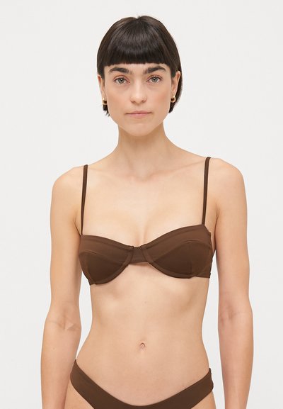 Bruine bikinitop met onderdelijke ondersteuning, voorzien van dunne verstelbare bandjes, een voorgevormd cupdesign en een gladde, matte textuur.