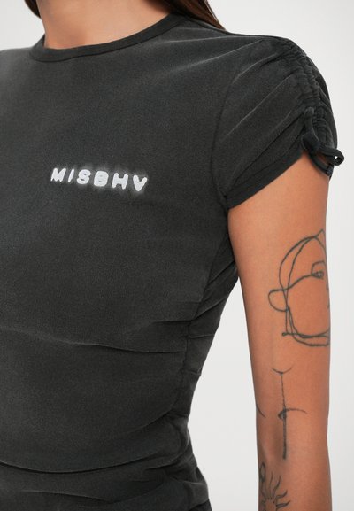 Must mustaga T-särk kogutud lühikeste varrukatega, mille vasakul küljel on valge "MISBHV" logo. Valmistatud pehmest, venivast kangast.